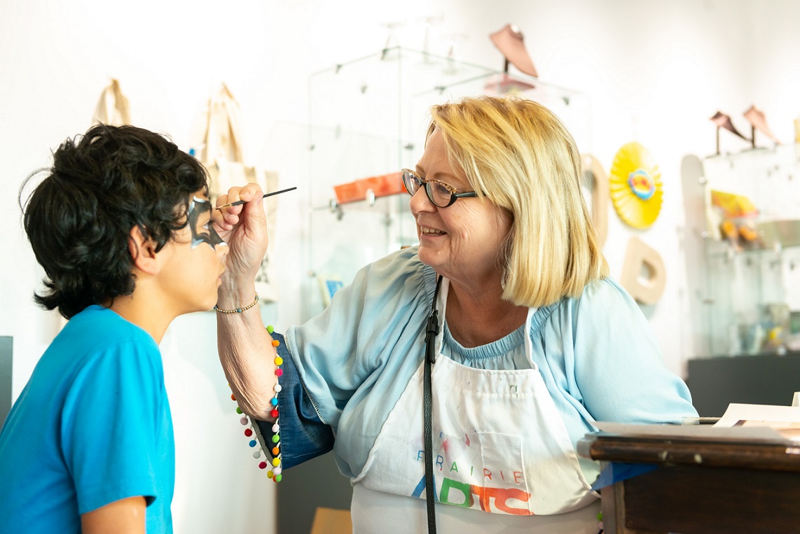 A child receives face paint at the Prairie Arts Center Open House
