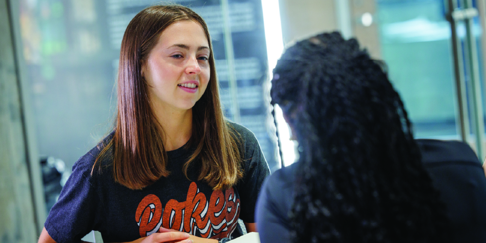 Student talks with another student inside a classroom