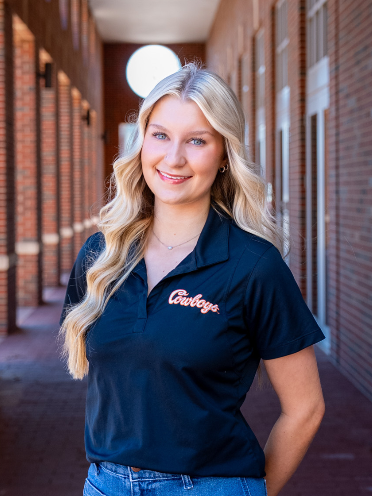 student posing behind ConocoPhillips OSU Alumni Center