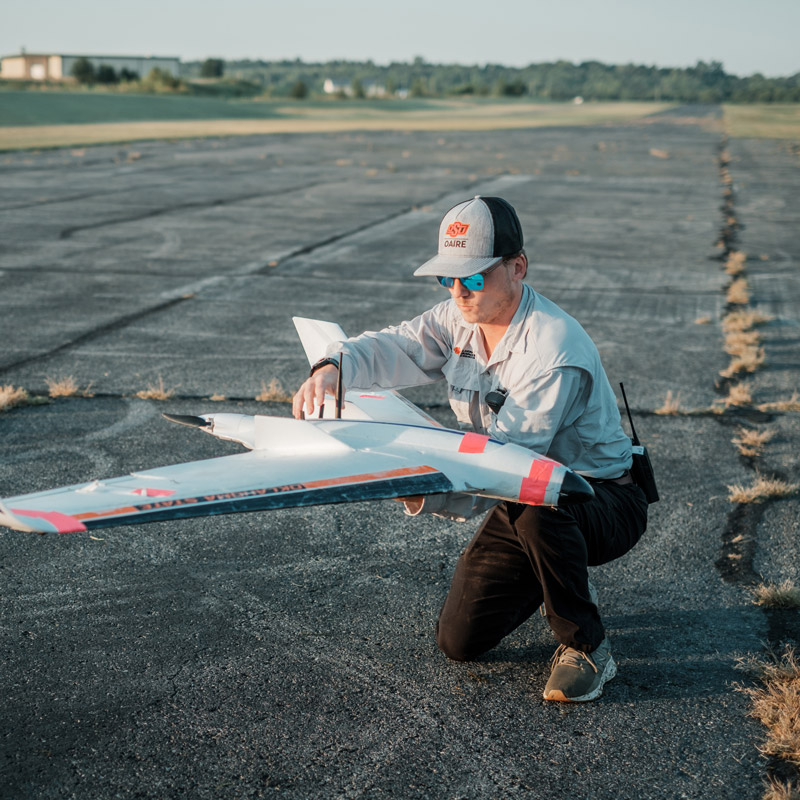 Student working on unmanned aircraft on tarmac