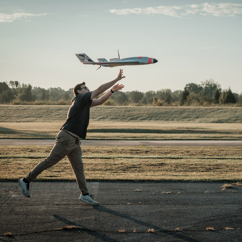 Student helping unmanned aircraft launch on tarmac