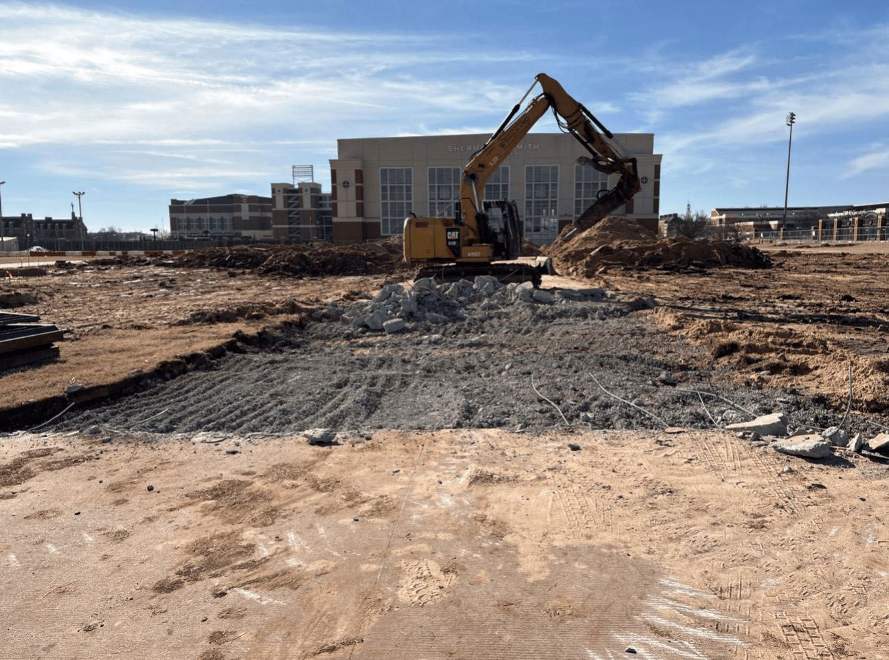 an excavator breaks up a concrete sidewalk
