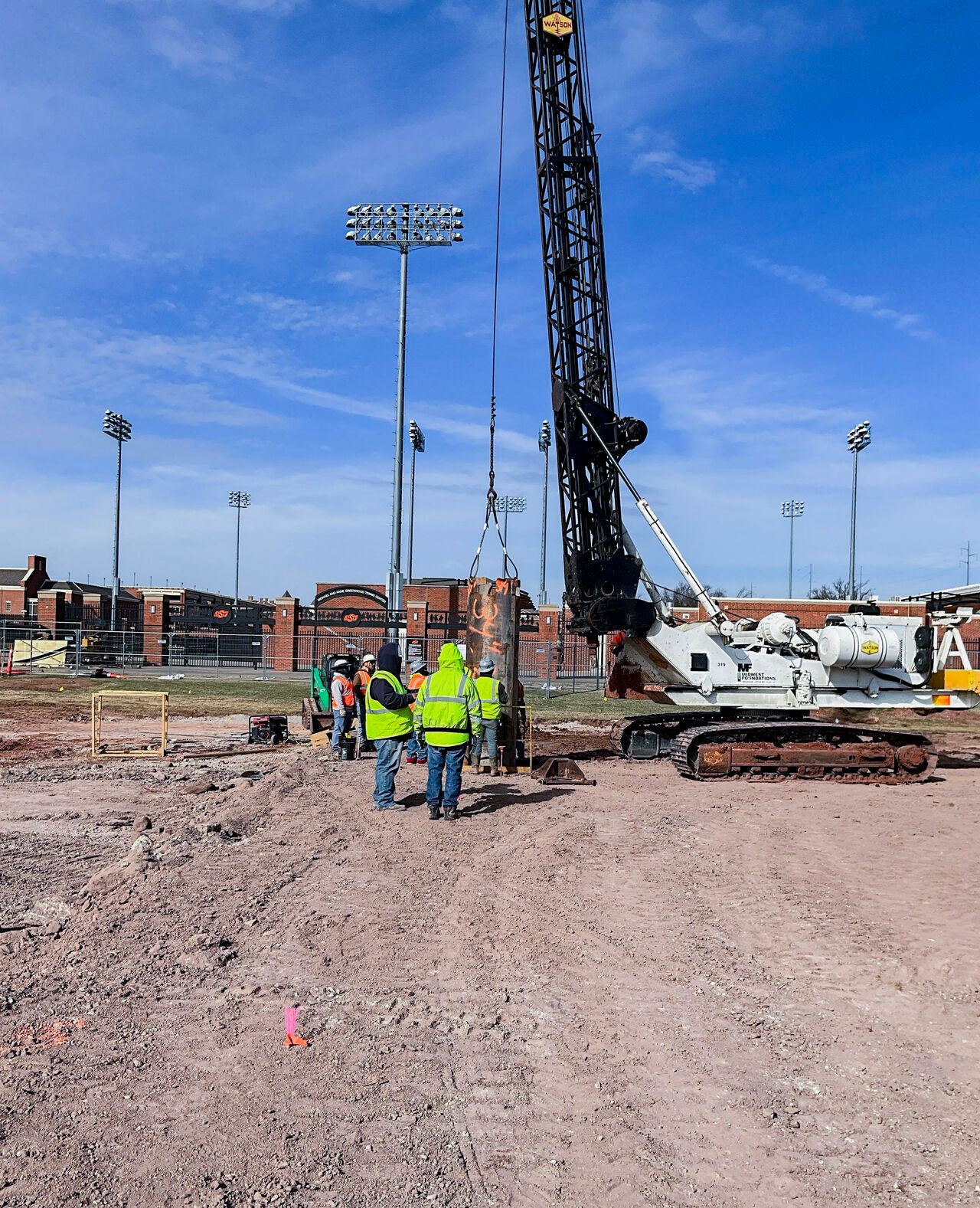 construction workers pour concrete piers for a building foundation