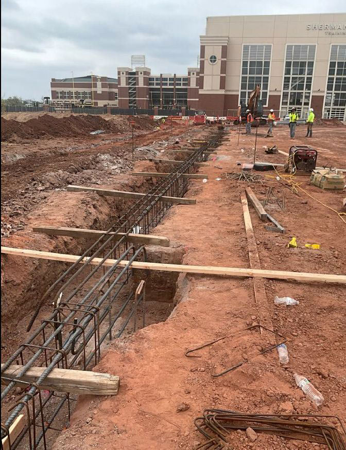 construction workers pour concrete piers for a building foundation