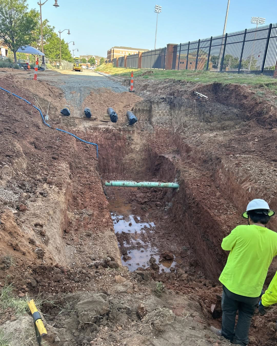 Construction workers inspect an excavated trench containing utility pipes and lines near the Boone Pickens Human Performance Innovation Complex at Oklahoma State University.
