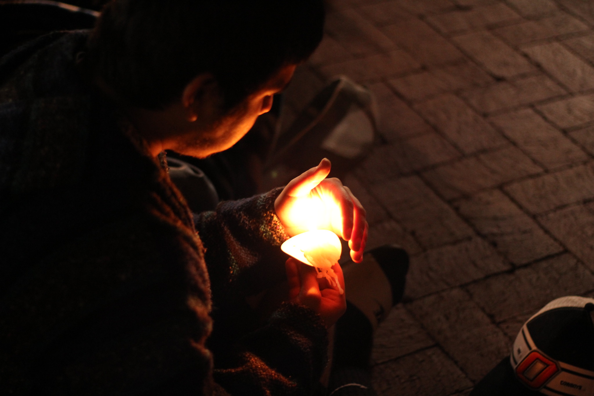 Photo over shoulder of student as he holds candle during parade vigil