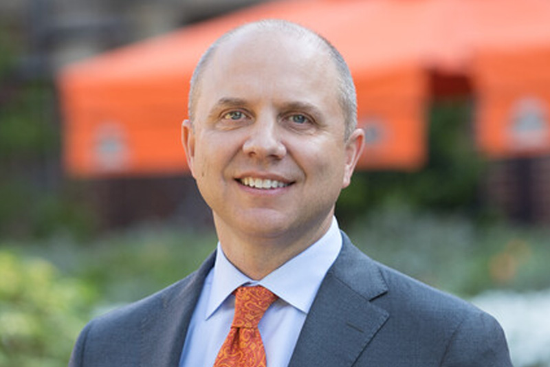 headshot, Jason ramsey in suit. garden in background