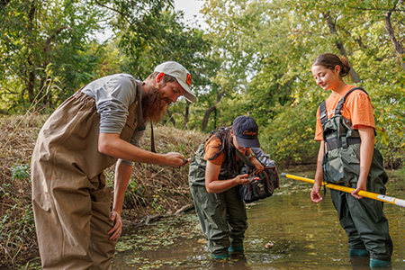 A group of students completes environmental testing in a creek.