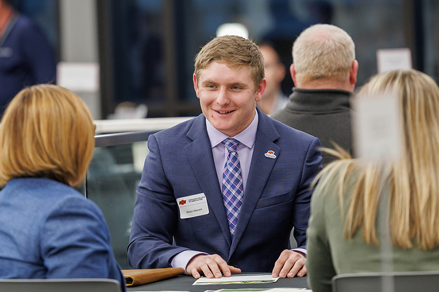 An agribusiness student speaking with employers at a networking event